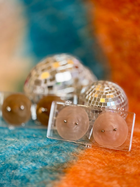 image of 2 of the nikkys nips pierced pasties for nipple piercings on a blue and orange backdrop