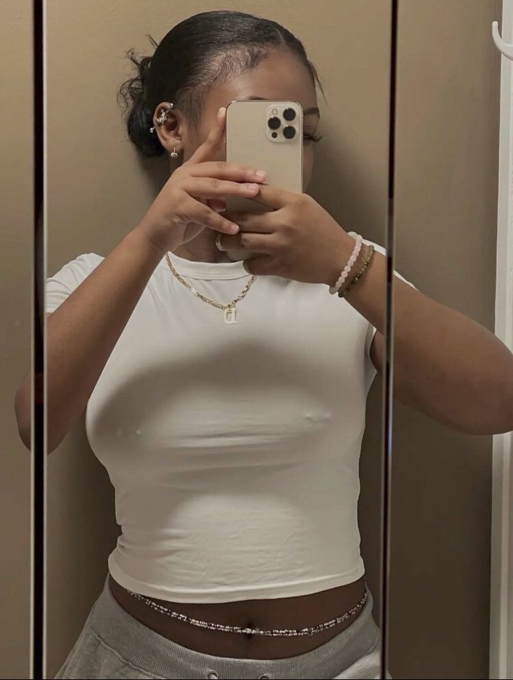 Young woman wearing a casual top demonstrating healed nipple piercings through clothing. Image has been cropped and edited appropriately to illustrate the article's educational content about piercing aftercare while maintaining modesty