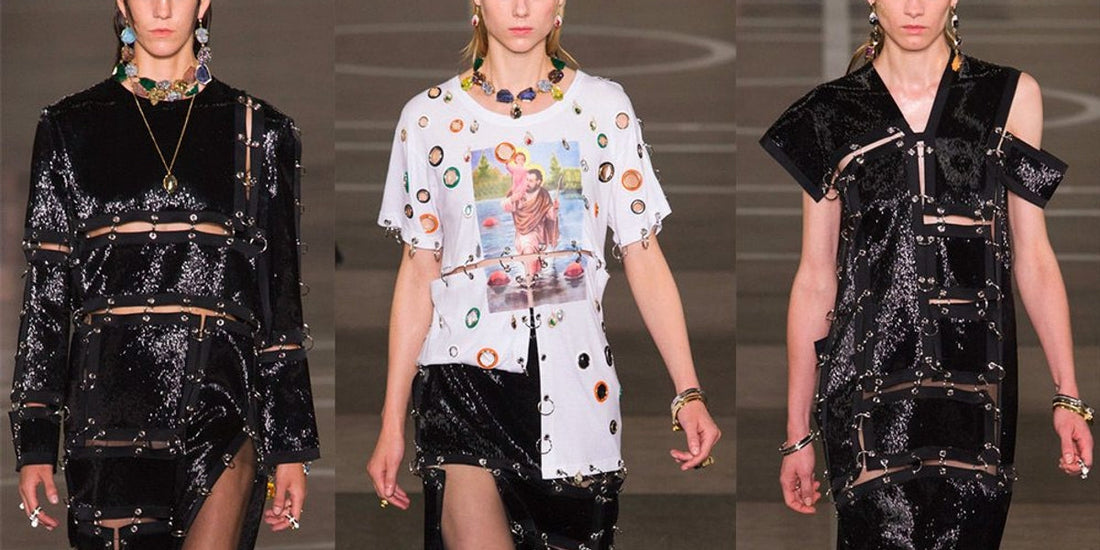 Three fashion models showcase looks from a collection featuring the 'pierced clothing' trend, where garments are embellished with numerous metal rings, eyelets, and strategically placed cutouts to mimic body piercings. 